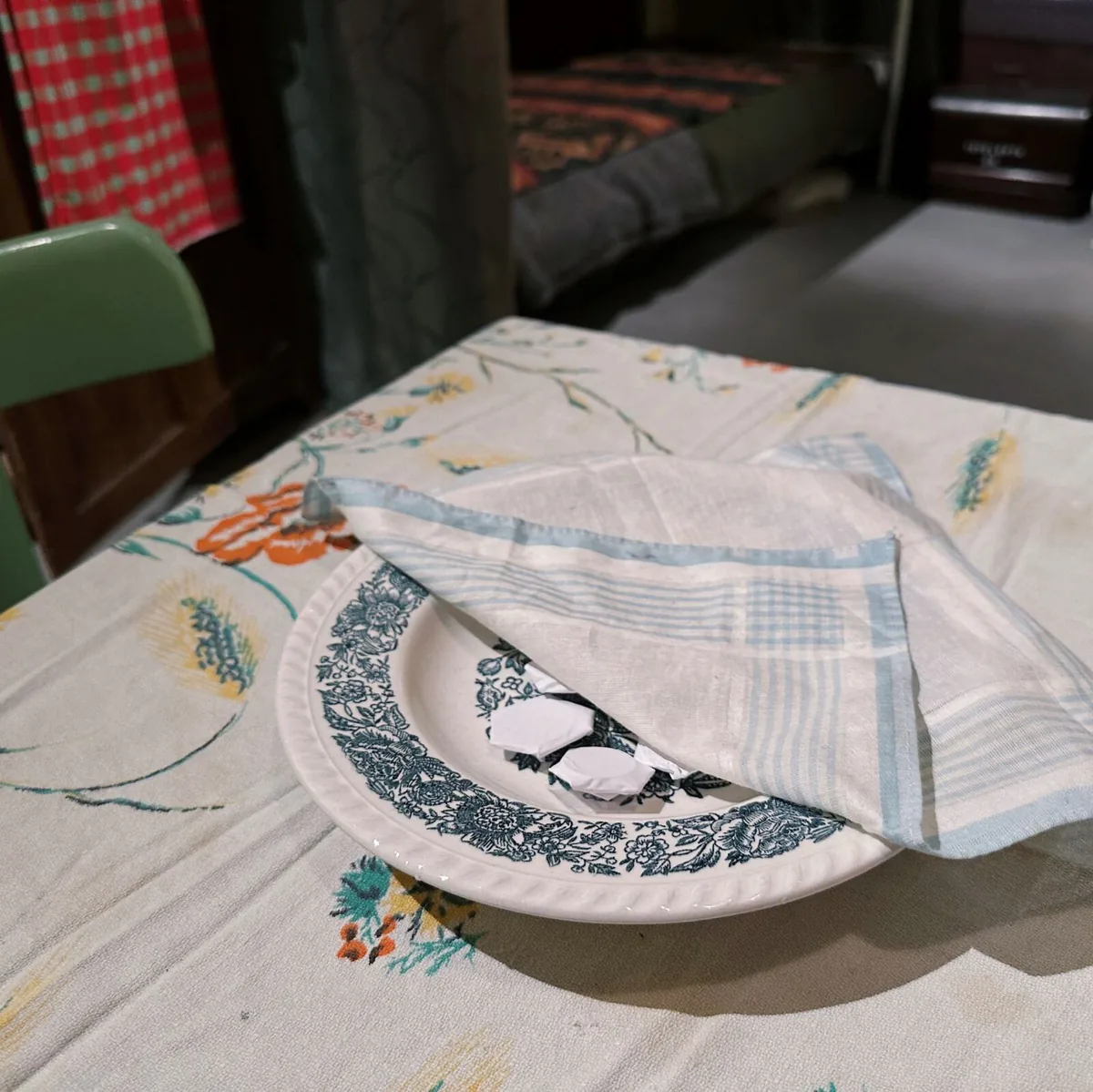 Een piring natzar met ingepakte geldmuntjes onder een kanten doek